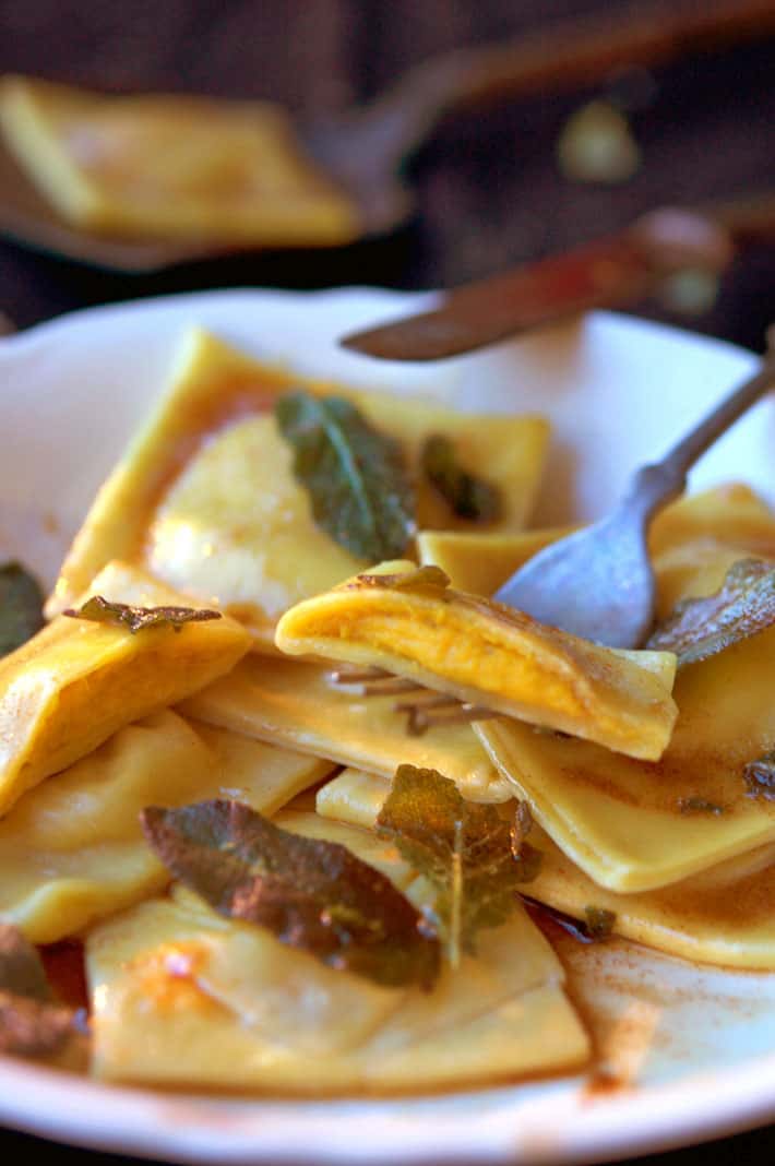 Homemade pumpkin ravioli on fork, with view of filling.