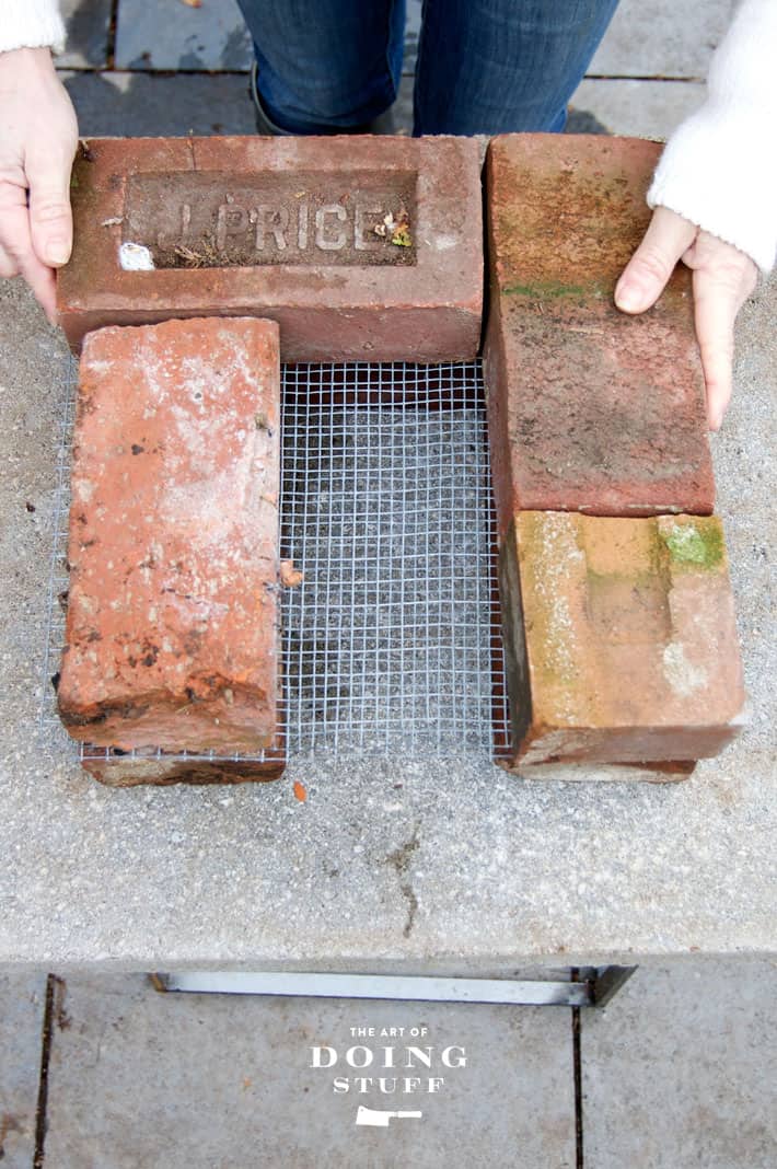 Setting antique bricks on top of hardware cloth for the base of a rocket stove.