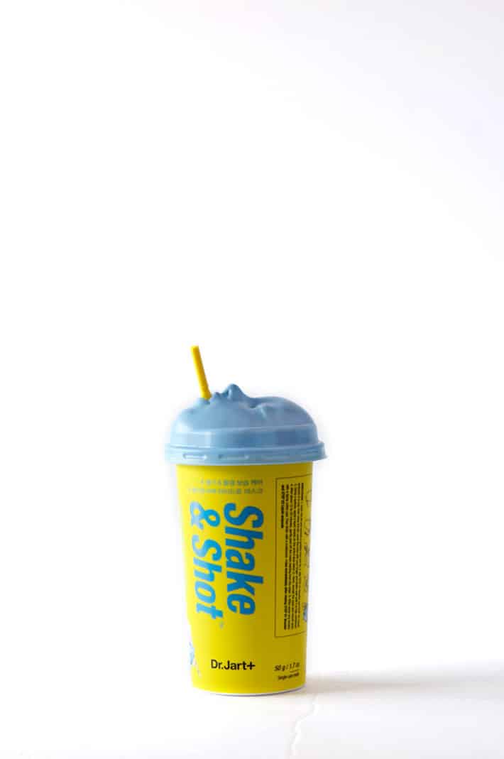 Yellow and baby blue paper cup with a plastic lid and straw. The plastic lid is in the shape of a face. Weird.