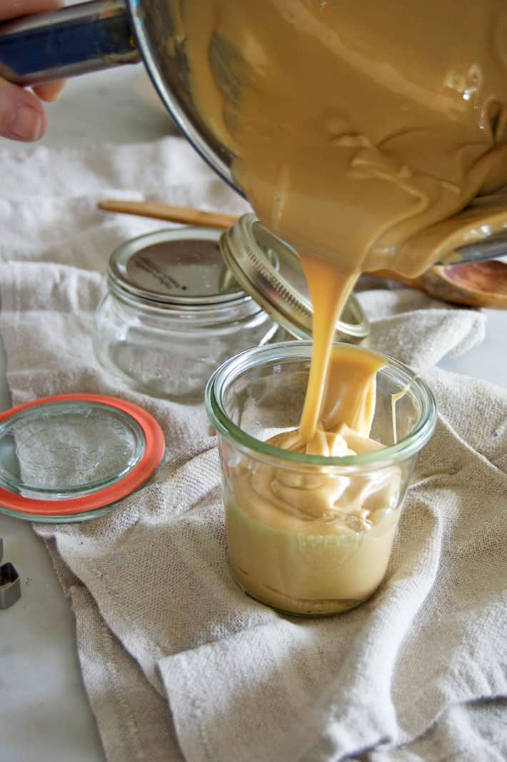 Pouring thick maple cream into Weck jars on linen tea towel.