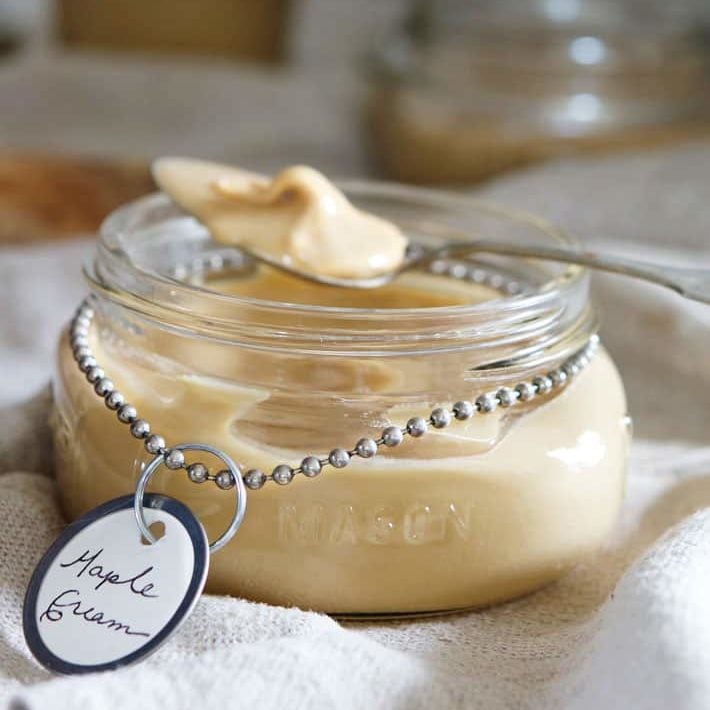 Spoonful of maple butter rests on jar of maple butter.