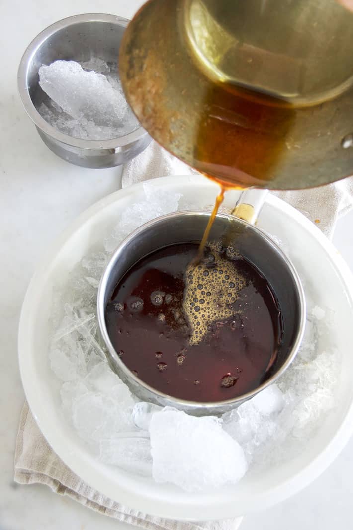 Pouring boiled maple syrup into pot set in ice water.