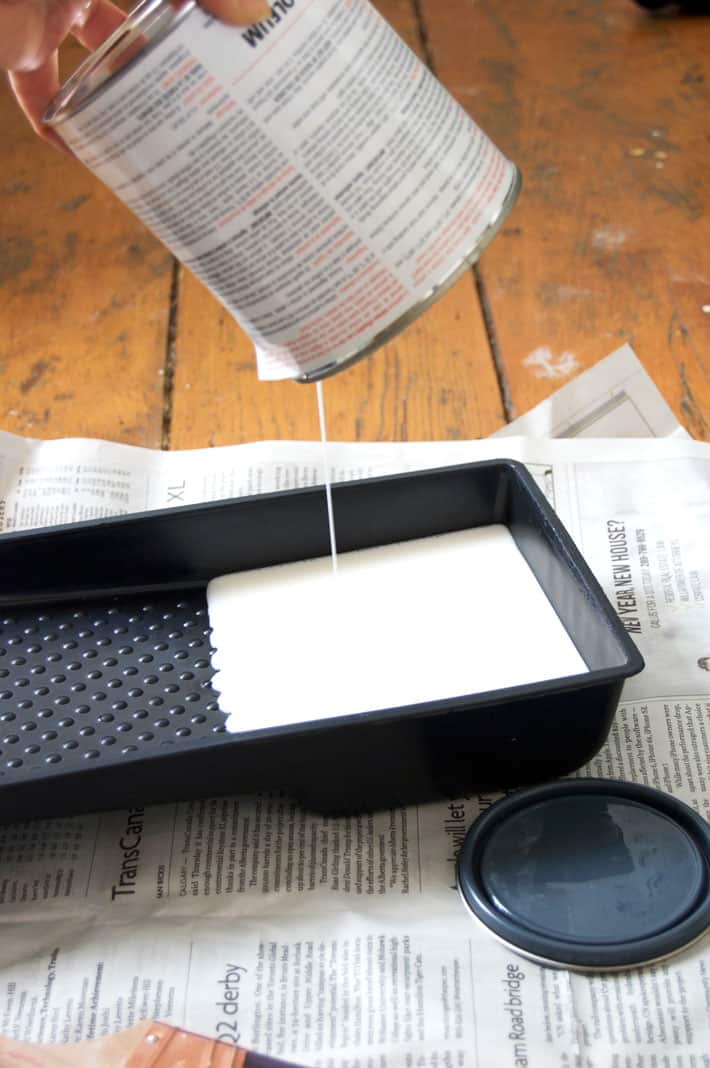 White paint dripping into small black paint tray.