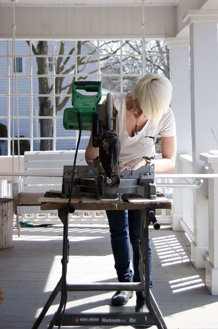 Karen Bertelsen cutting wood to length on outdoor porch for interior shutters.