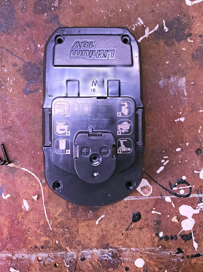 Overhead view of a rechargeable drill battery on paint splattered work bench.