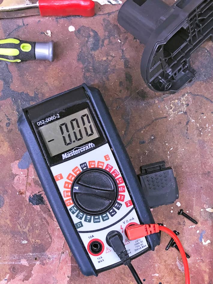 How to fix a new 18V battery that won't recharge. Multimeter on workbench with tools around.