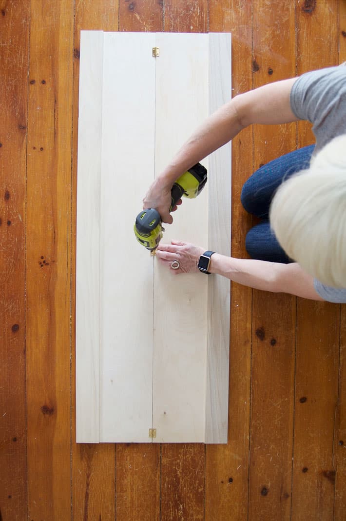 Screwing small brass hinges into interior shutters.