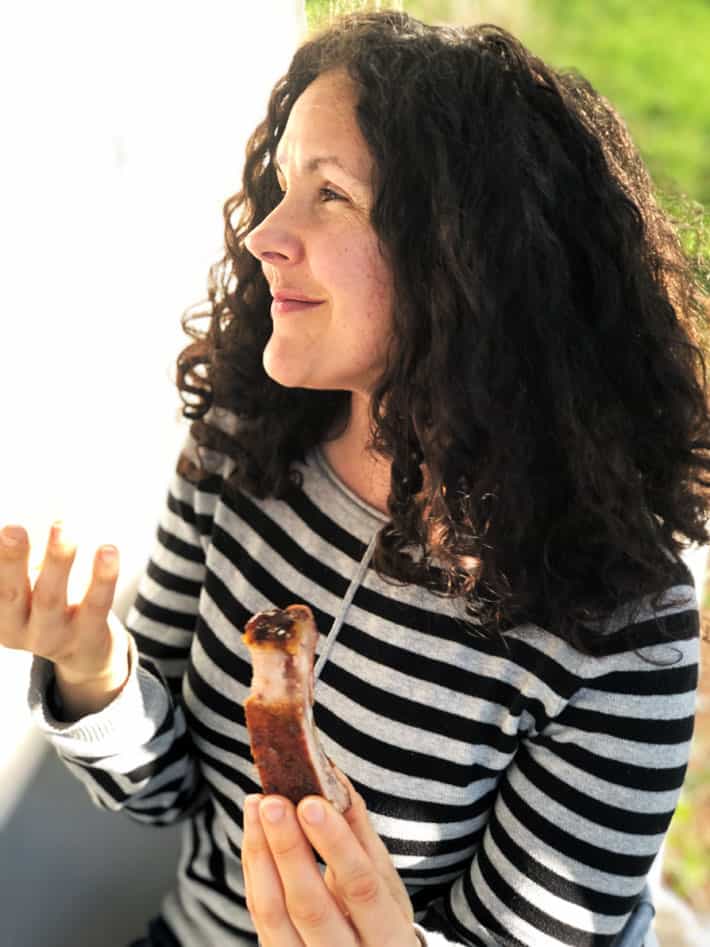 Woman with long curly hair eating ribs.