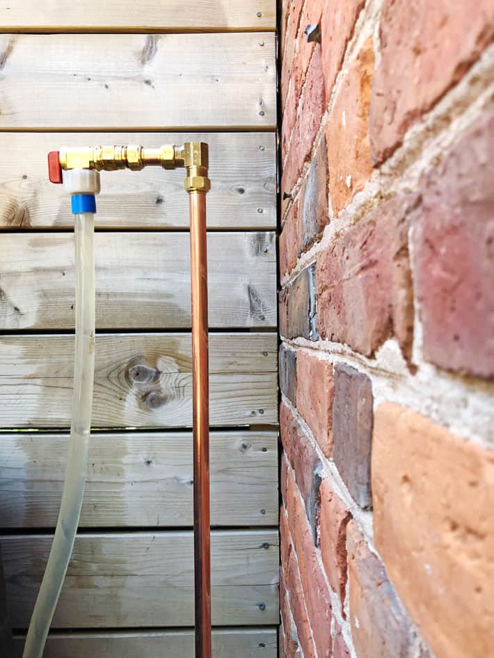 Newly replaced copper water pipe, outside against brick wall.