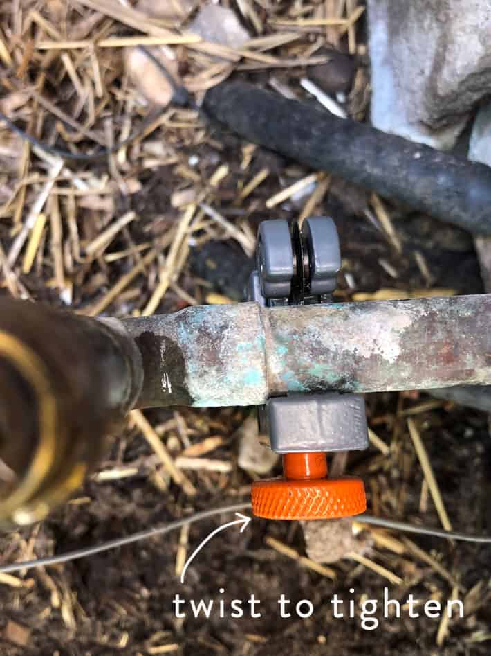 Cutting old copper pipe with a pipe cutter.
