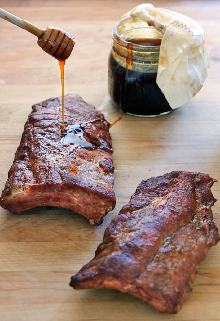 Gooey sauce being drizzed with honey dripper onto ribs.