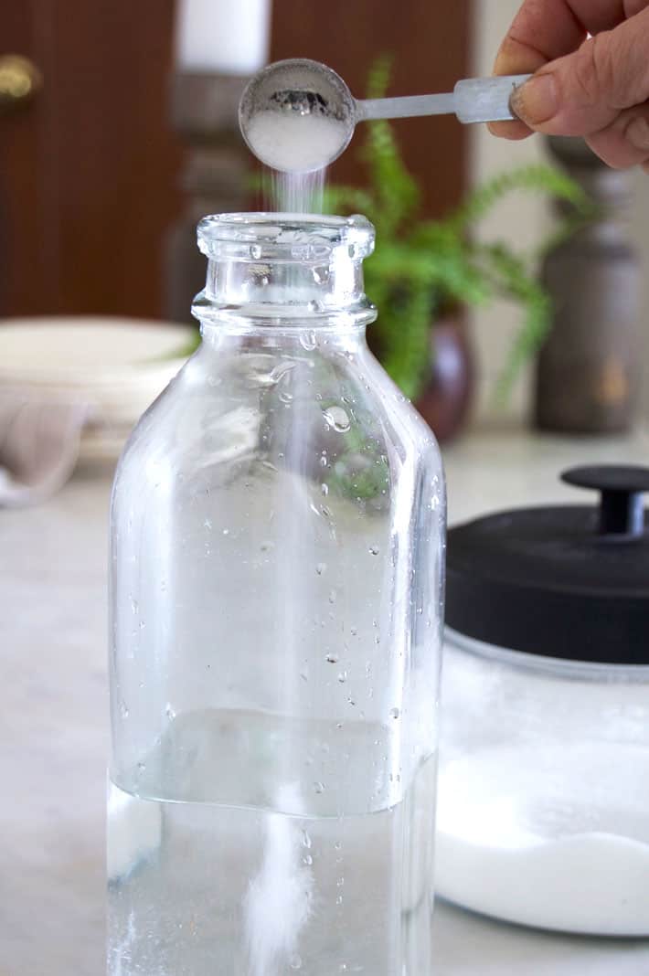 Pouring sugar into glass milk bottle.
