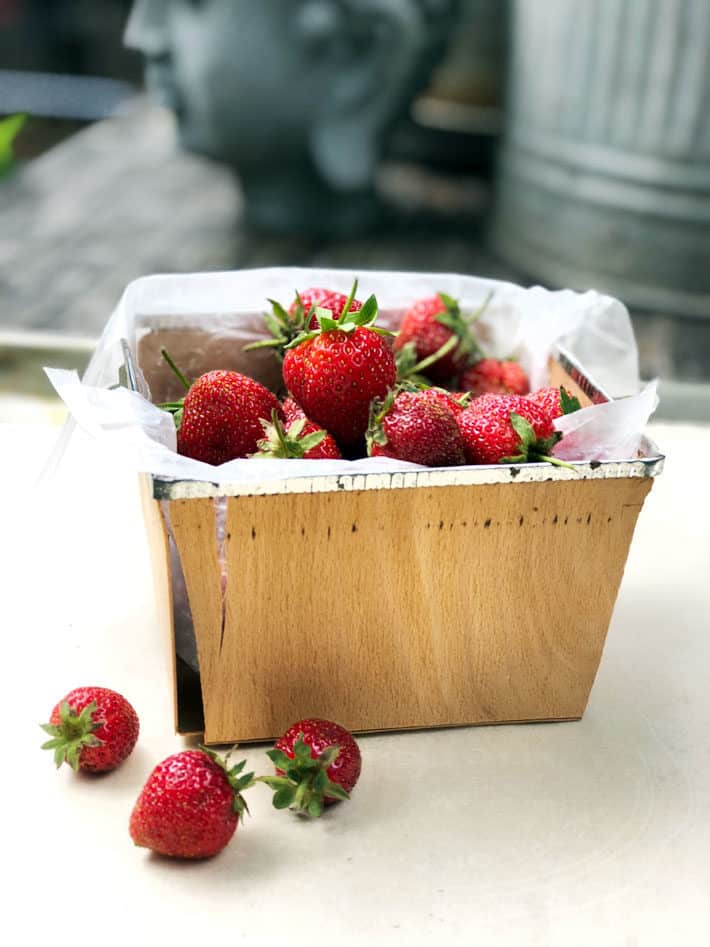 Picturesque strawberries in an old fashioned wood pint basket.