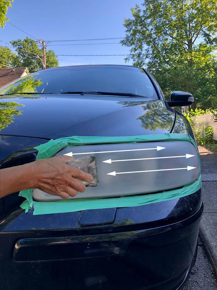 Sanding car headlight in a horizontal motion with 800 grit sandpaper.