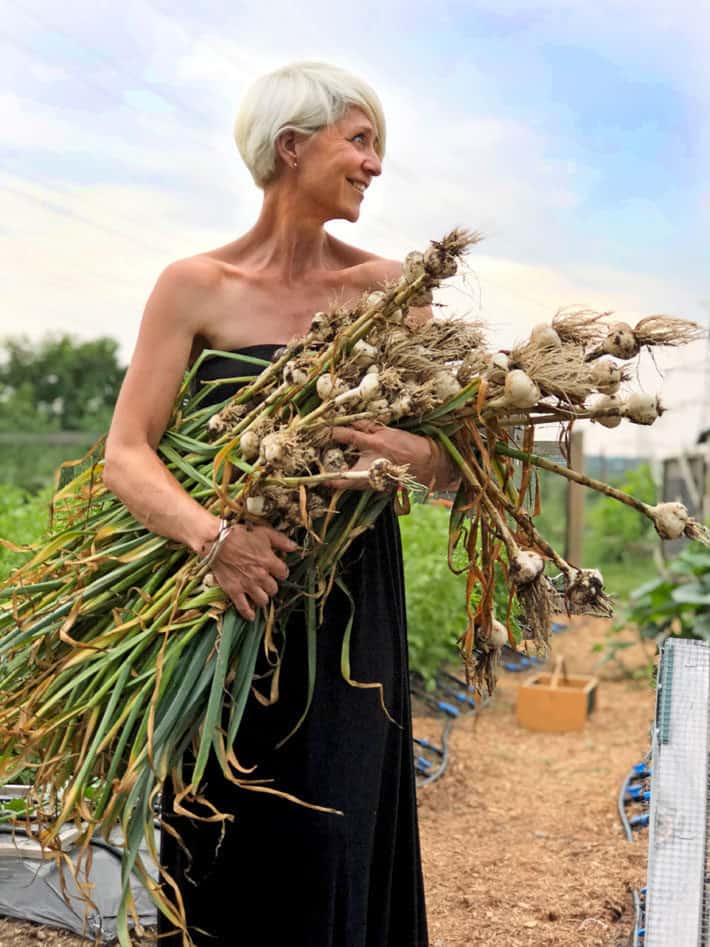 Karen Bertelsen holding an armload of some of the garlic she grew.