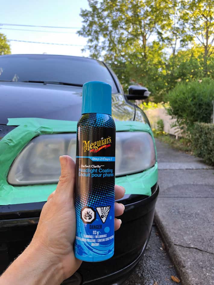 Meguiar's headlight coating can held up in front of cloudy headlight.