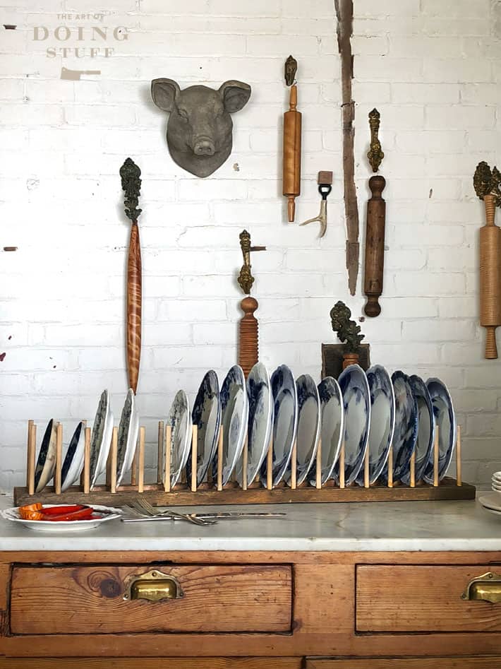 DIY plate rack in front of white brick wall.