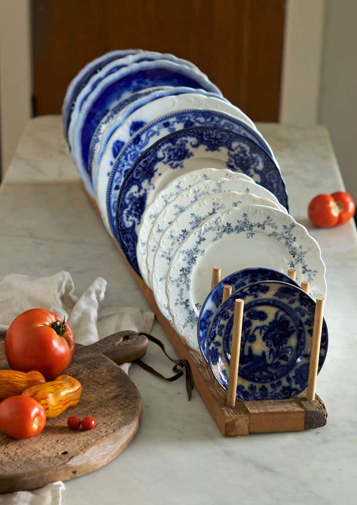 Slightly overhead shot of flow blue and transferware china in rustic wood plate rack.