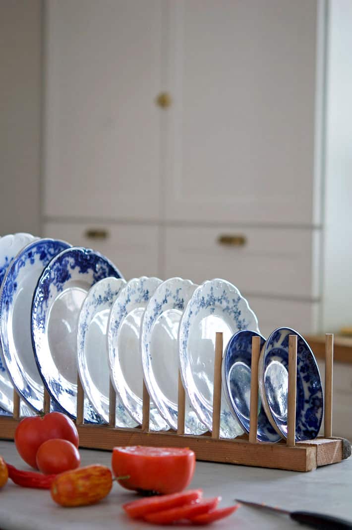 DIY plate rack on counter filled with flow blue plates.