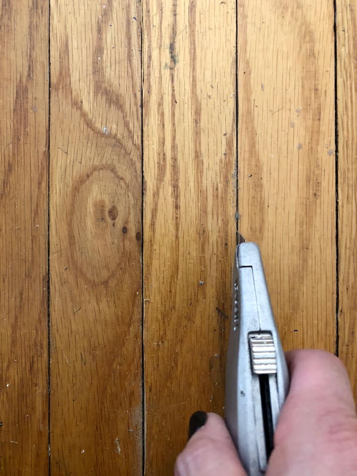 Cutting between crack in tongue and groove  hardwood with boxcutter.
