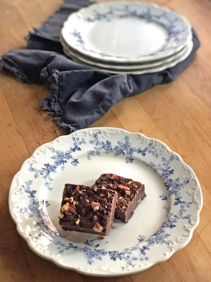 Looking down on a blue and white transferware plate with two chocolate brownies sitting on it.