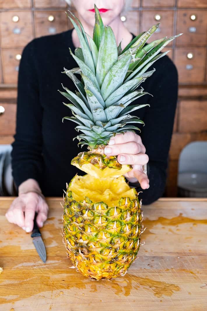 The top of a pineapple being removed.