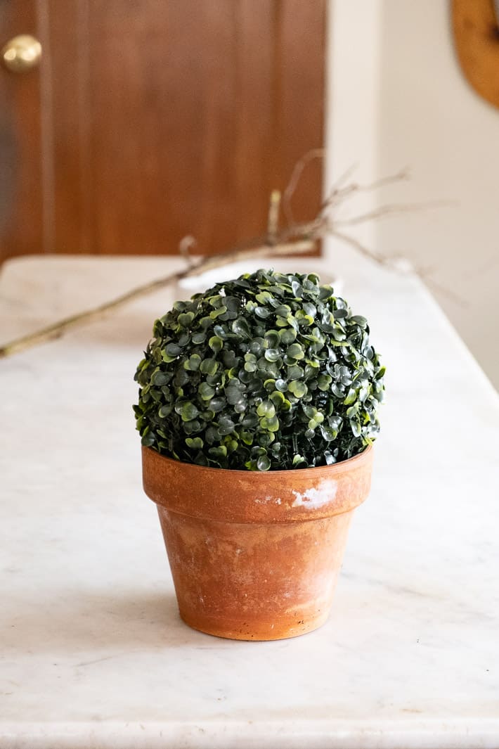 Artificial topiary ball displayed in old clay pot with patina.