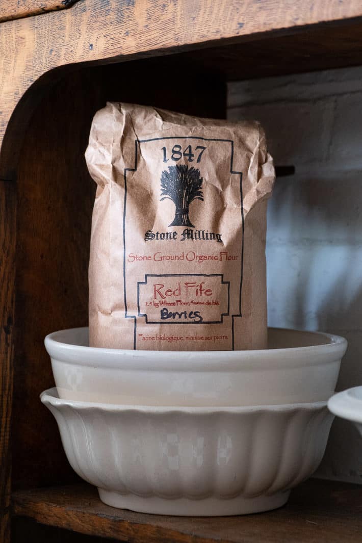 A paper bag of Red Fife Wheat berries from 1847 Stone Milling sits in an ironstone bowl.