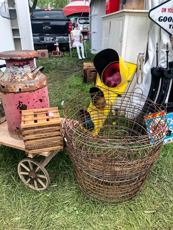 As assortment of finds at the antique show including rustic pink milk urn, wooden egg crate, antique traffic lights and wire baskets. 