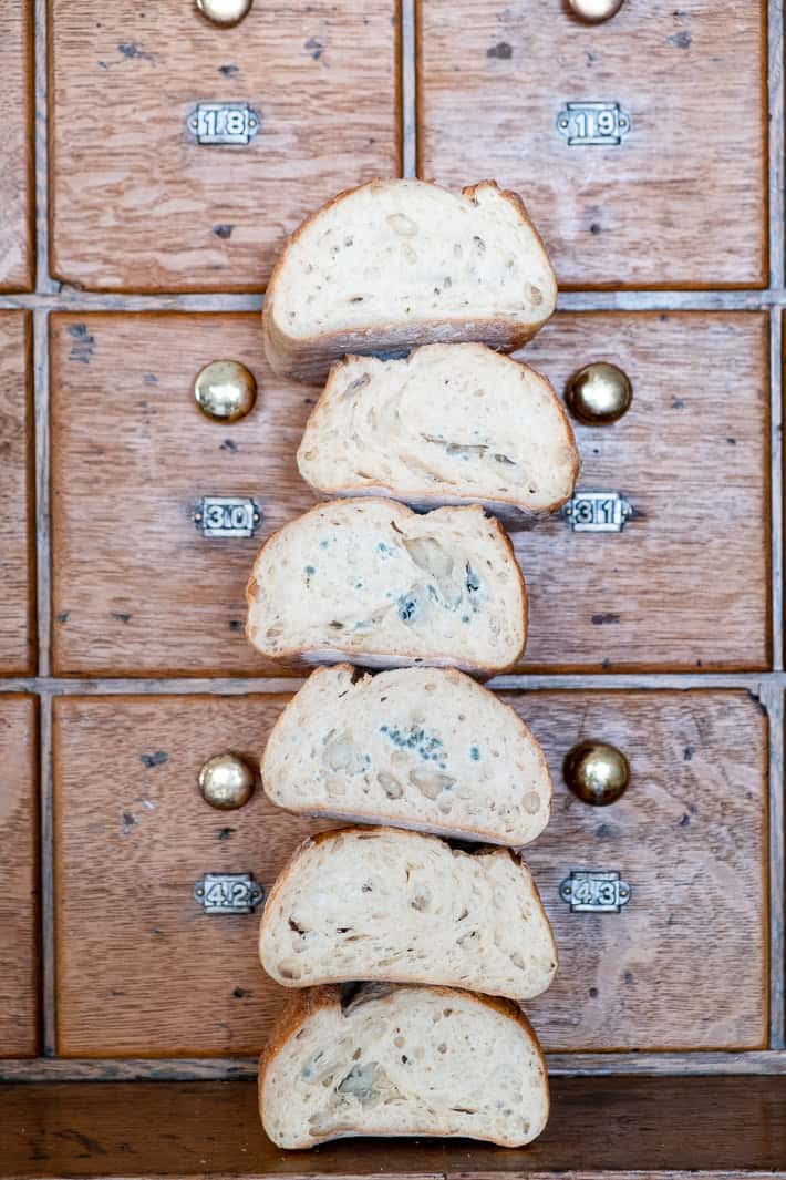 Varying degrees of mold forming on cut ends of stacked loaves of bread.