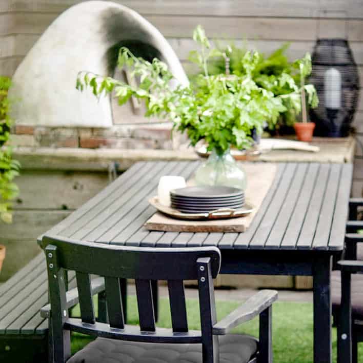 5 epic summer projects to make your season fantastic. Elegant black, wood outdoor table set up in front of a homemade cob pizza oven and hearth.