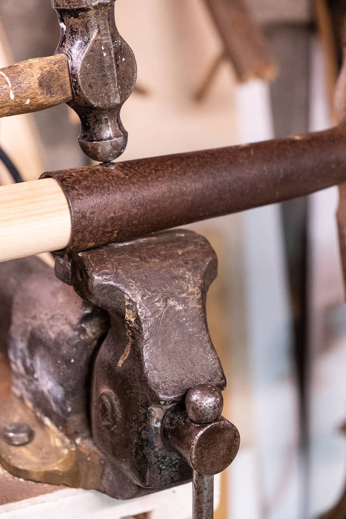 Hammering the end of a rivet end to flatten it out over a shovel handle.