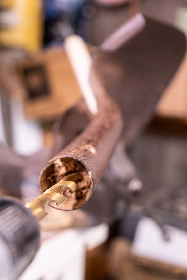 Drilling out the remnants of a shovel handle from the shaft of a rusted shovel head.