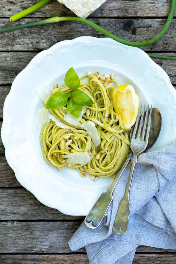 Garlic Scape pesto - the pesto that will ruin you for all other pestos. Garlic Scape Pesto on linguine in an antique ironstone bowl, topped with shavings of parmesan, basil leaves and a wedge of lemon.