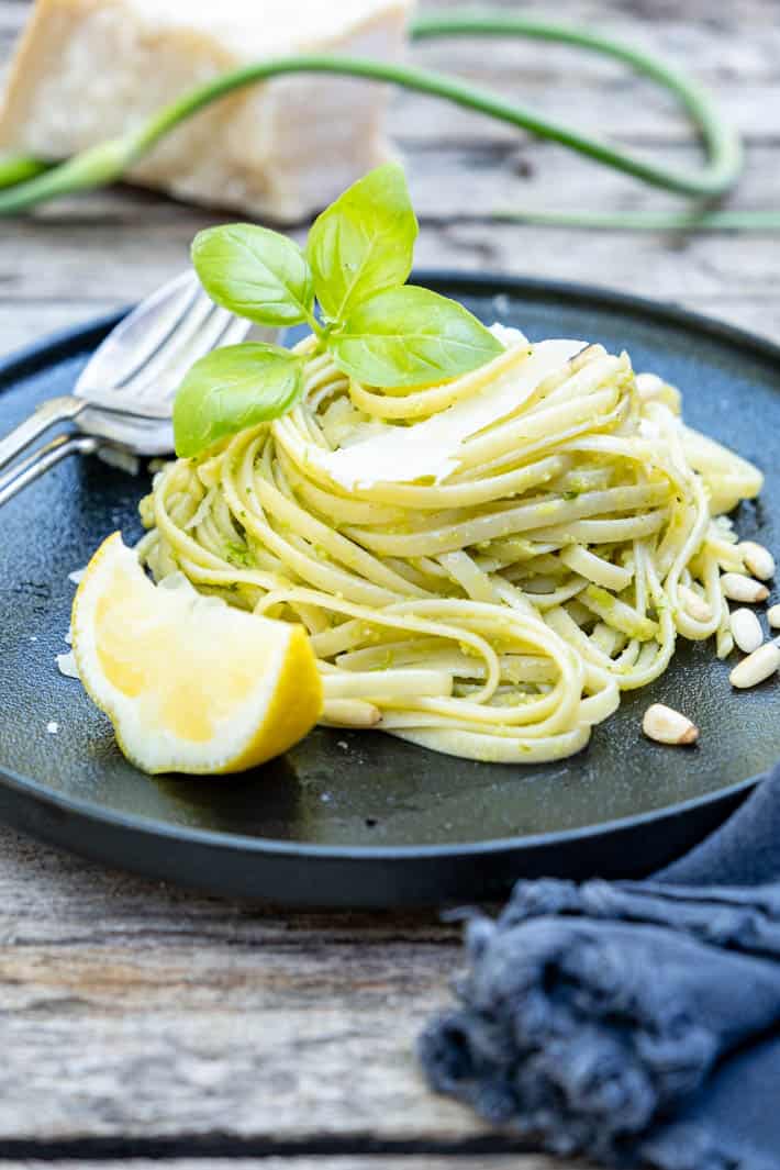 Garlic Scape pesto - the pesto that will ruin you for all other pestos. A twirl of linguine dressed with garlic scape pesto on a black plate set on a rough wood table.