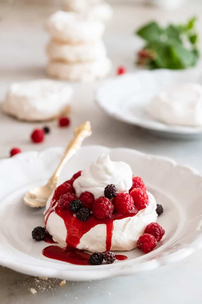 Mini Pavlova with fresh berries, whipped cream and raspberry compote.