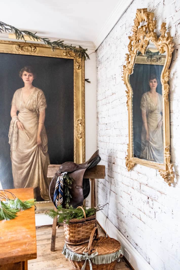 Life sized antique oil painting of a woman, with a saddle and saddle stand in front.