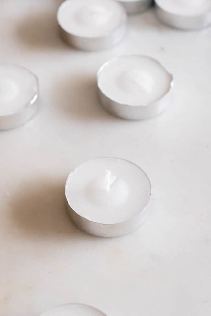 Several tea lights set on a marble countertop.