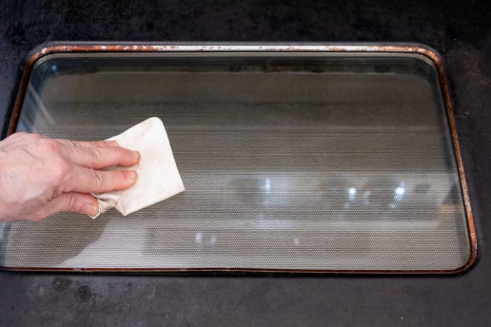 Cleaning the glass of an oven door without chemicals using only a damp MiraFiber cloth.