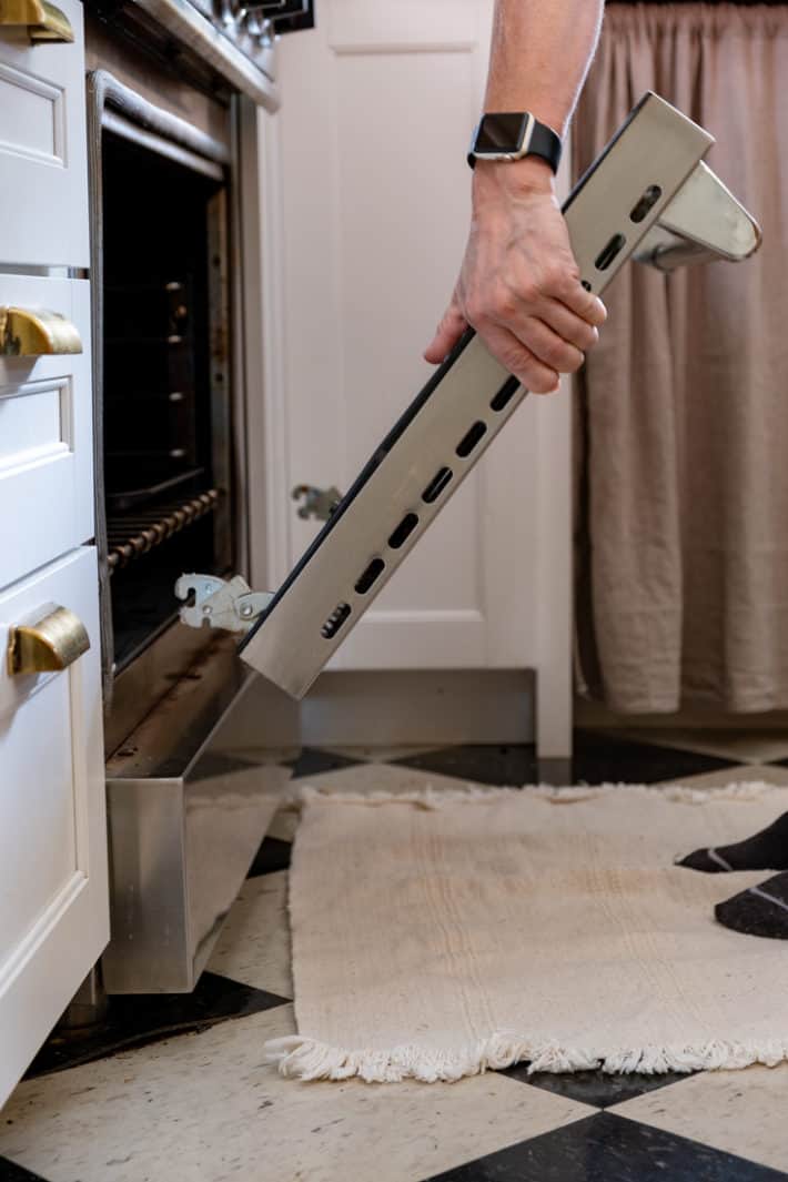 Removing an oven door by grabbing it by the sides and lifting it off.