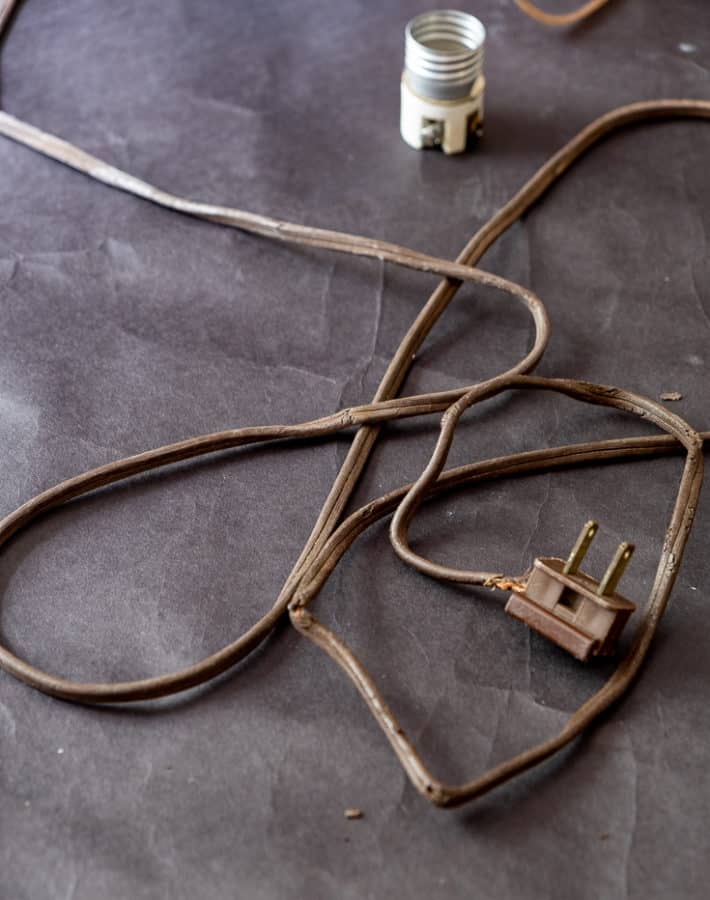 Old brown lamp cord with exposed wires at the plug end and throughout the cracked brittle wire.