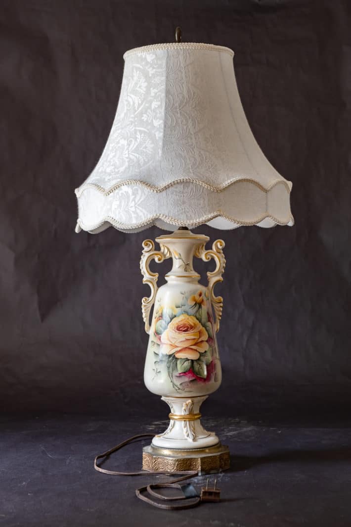 Vintage ceramic lamp with shade and hand painted roses on a black background.