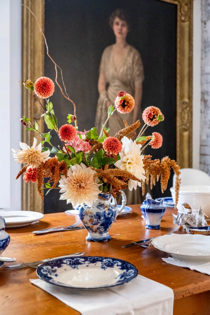 A Thanksgiving centrepiece of ice cube dahlias, hot biscuits amaranth and cornel bronze dahlias sits in a flow blue jug.