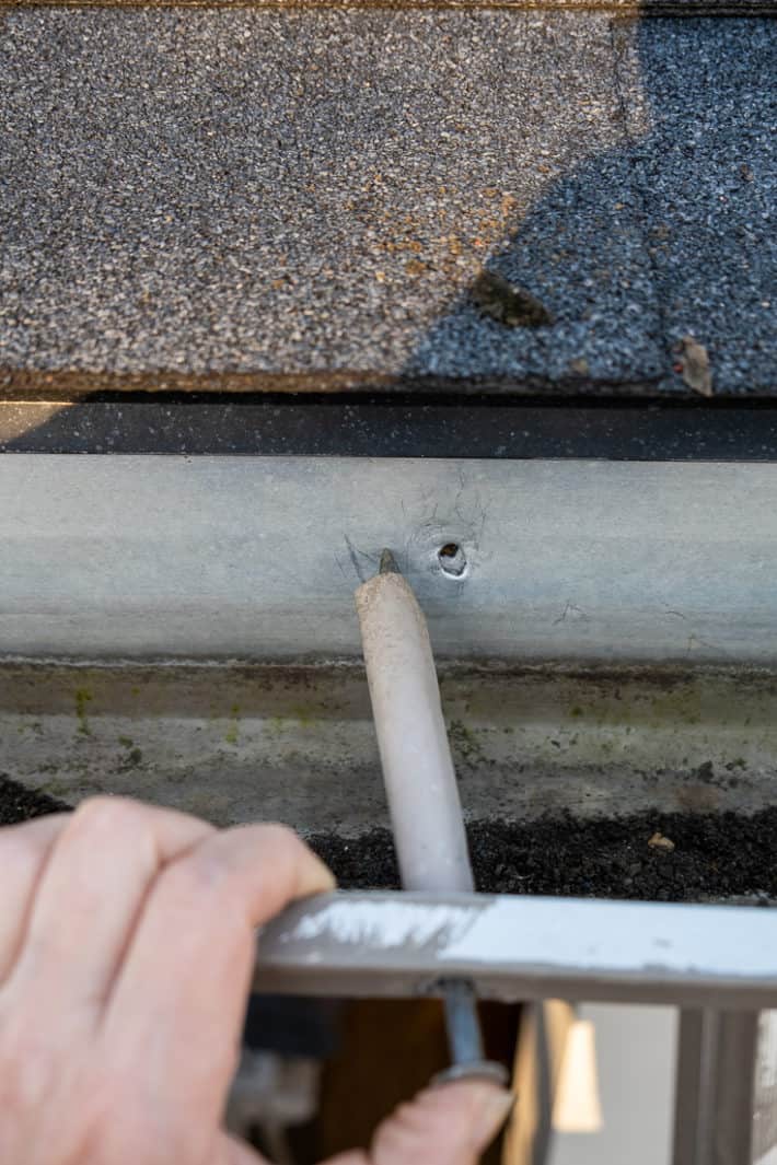 Lining up a gutter spike to the left of its original hole.