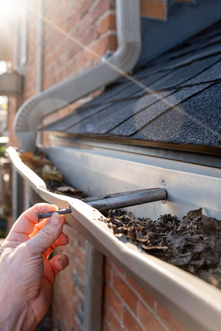 Reinserting a gutter spike into its hole to hammer back in.