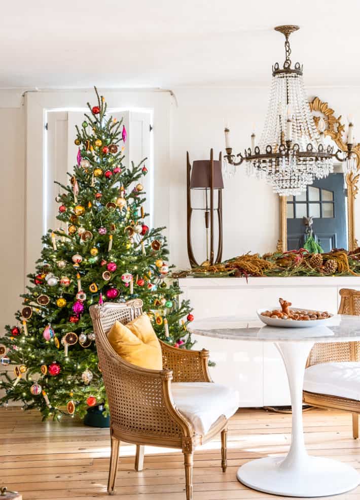 Front foyer of heritage home at Christmas, with traditionally decorated Christmas tree behind modern marble tulip table and crystal chandelier.