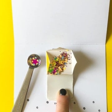 Filling glitter bomb mechanism with confetti and glitter