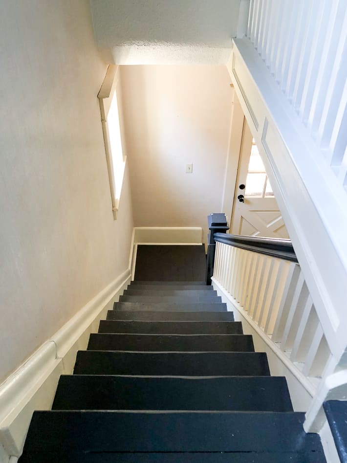 Painted staircase with black, newel post, bannister and white spindles and risers.