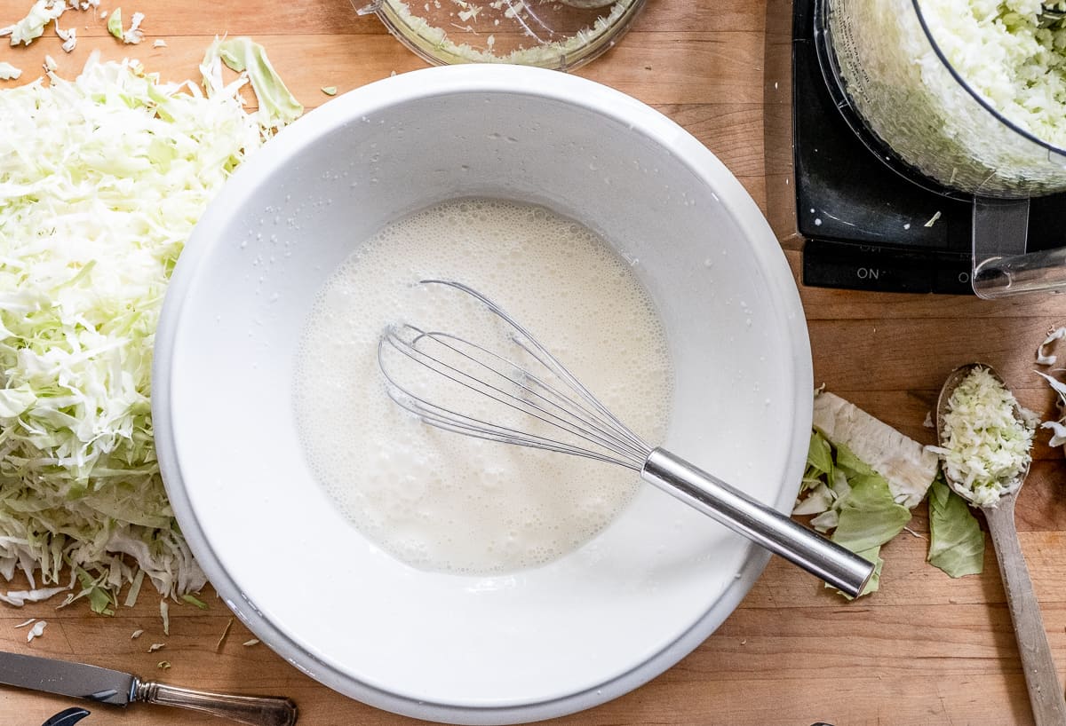 Fully mixed creamy coleslaw dressing in ironstone bowl.