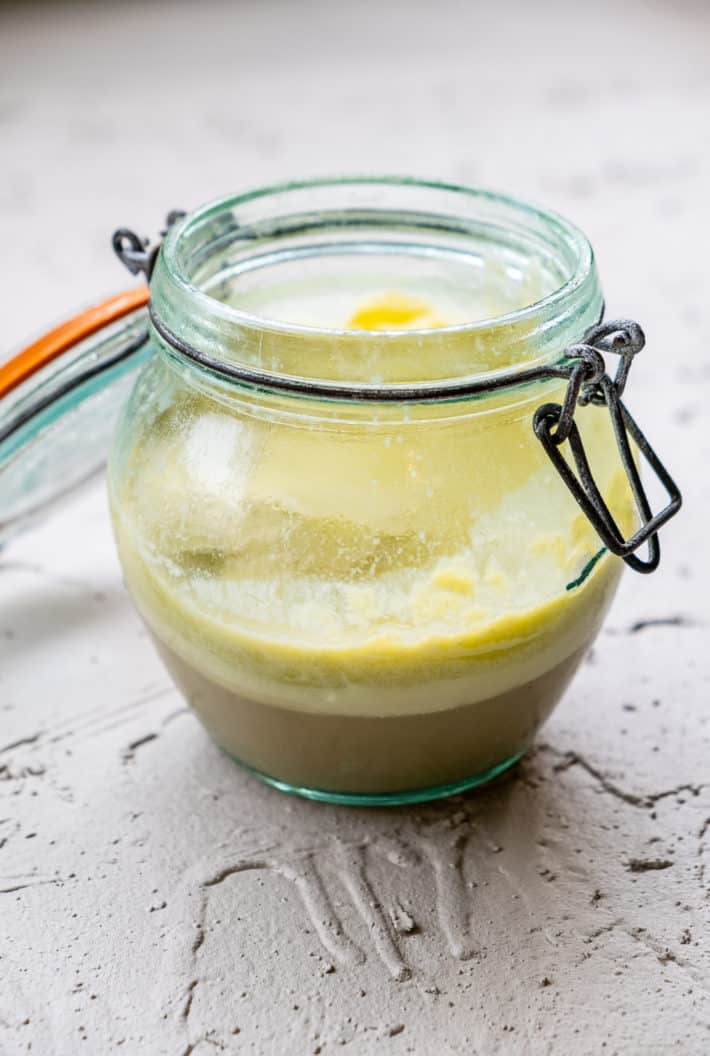 Hardened butter sitting atop of greenish waste water in a flip top mason jar.